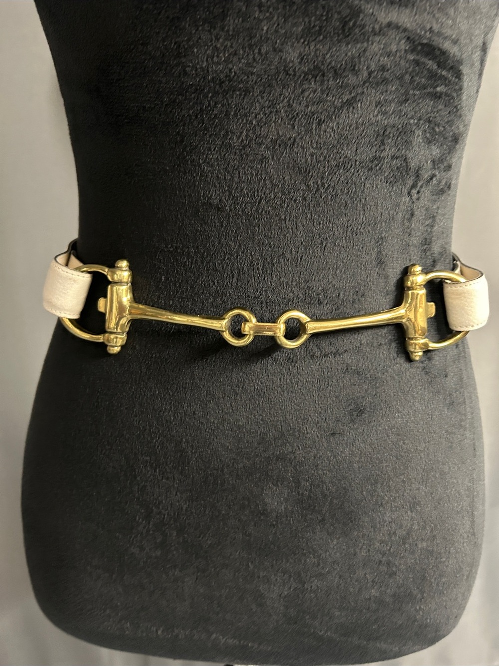 Bridle bit buckle on off-white leather belt. Small